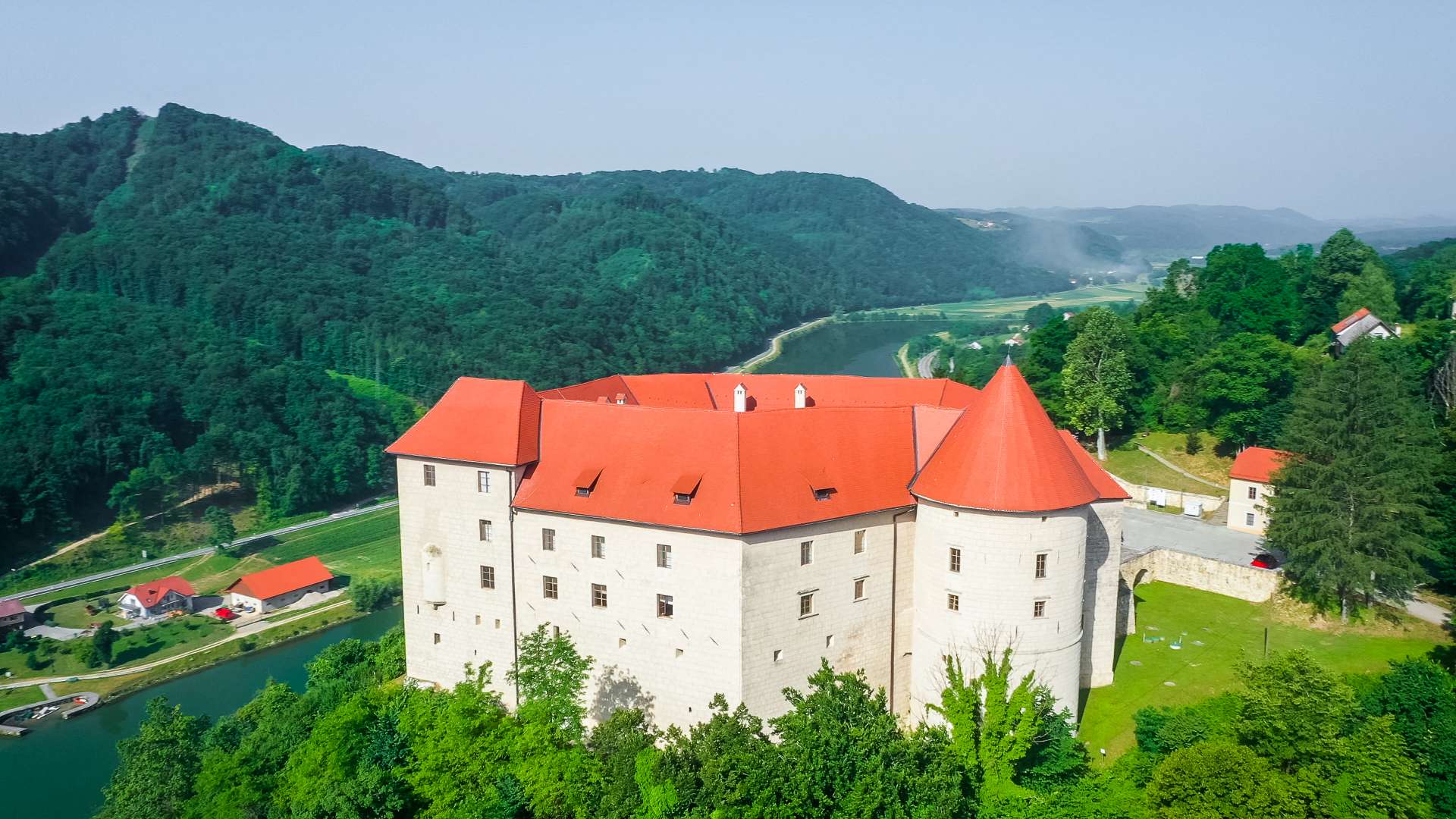 Grad Rajhenburg ob reki Krki sredi zelenega okolja